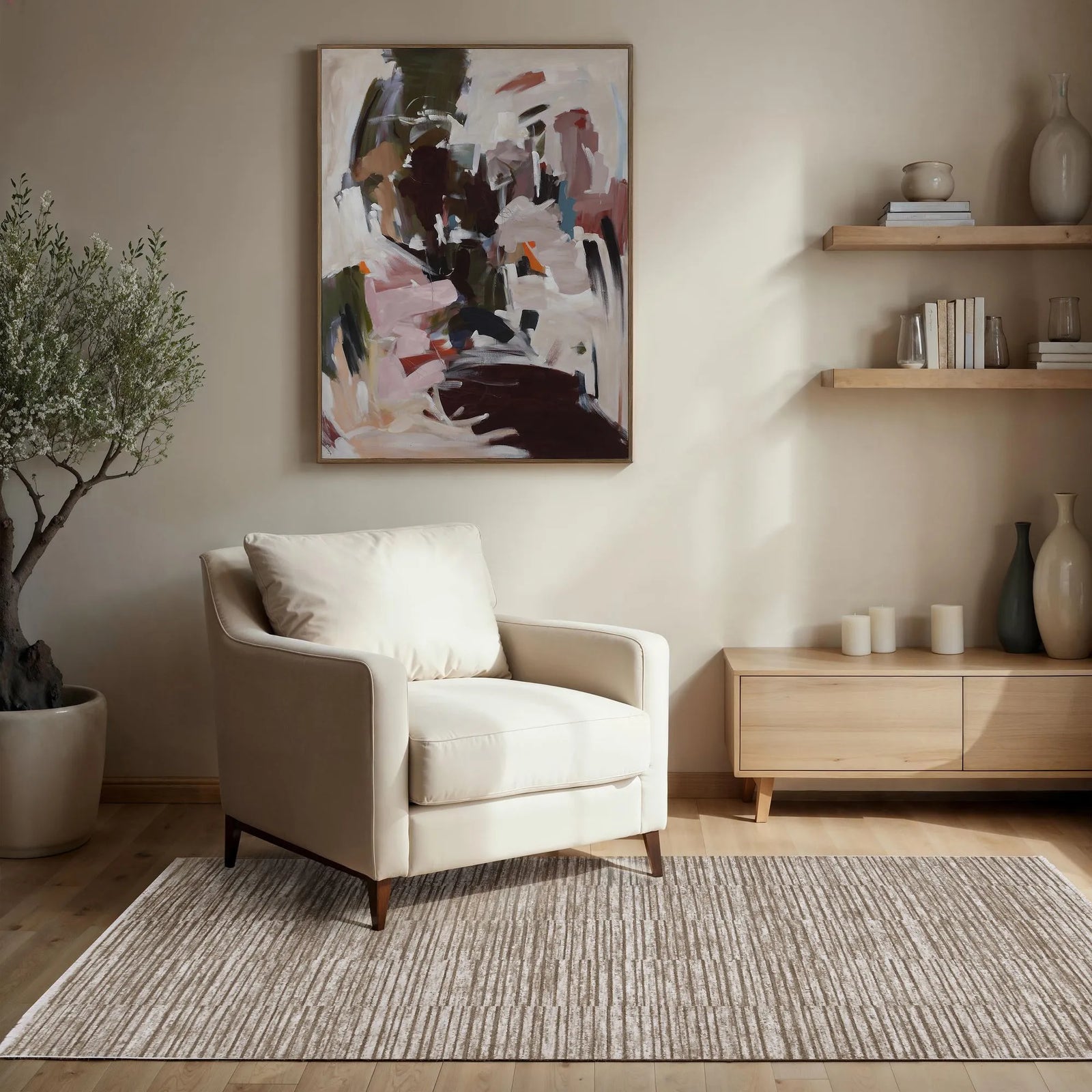 Modern living room with a beige armchair, abstract painting, and wooden shelves.