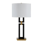 Table lamp with a white shade, black and gold base on a white background