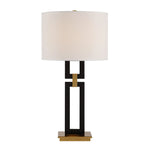 Table lamp with a black and gold base and white shade on a white background