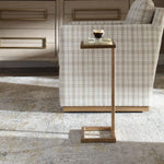 Small side table with a glass top next to a chair in a room with wooden flooring.