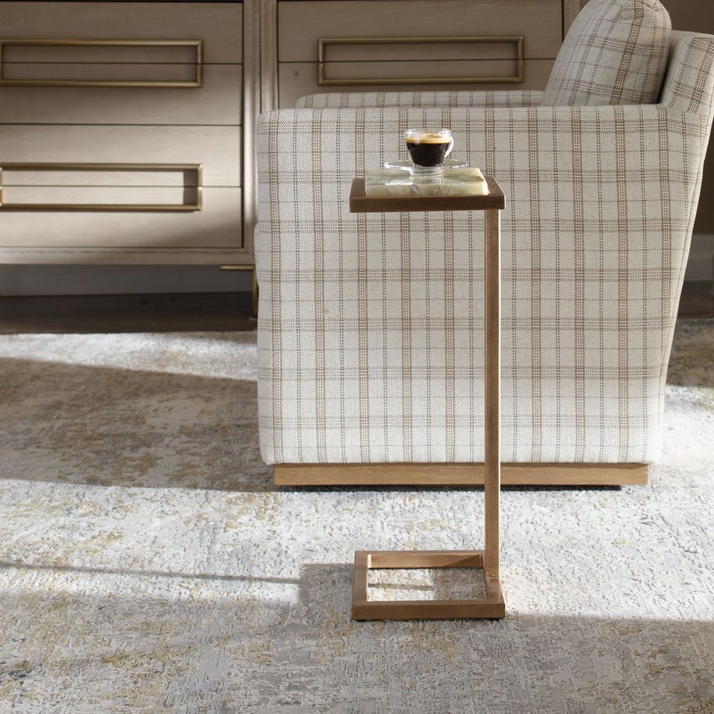 Small side table with a glass top next to a chair in a room with wooden flooring.