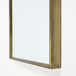 An oval-shaped full-length mirror with a gold antiqued metal frame.