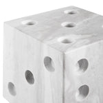 close-up to a gray marble dice decor object with multiple holes on each face, resembling dice numbers.