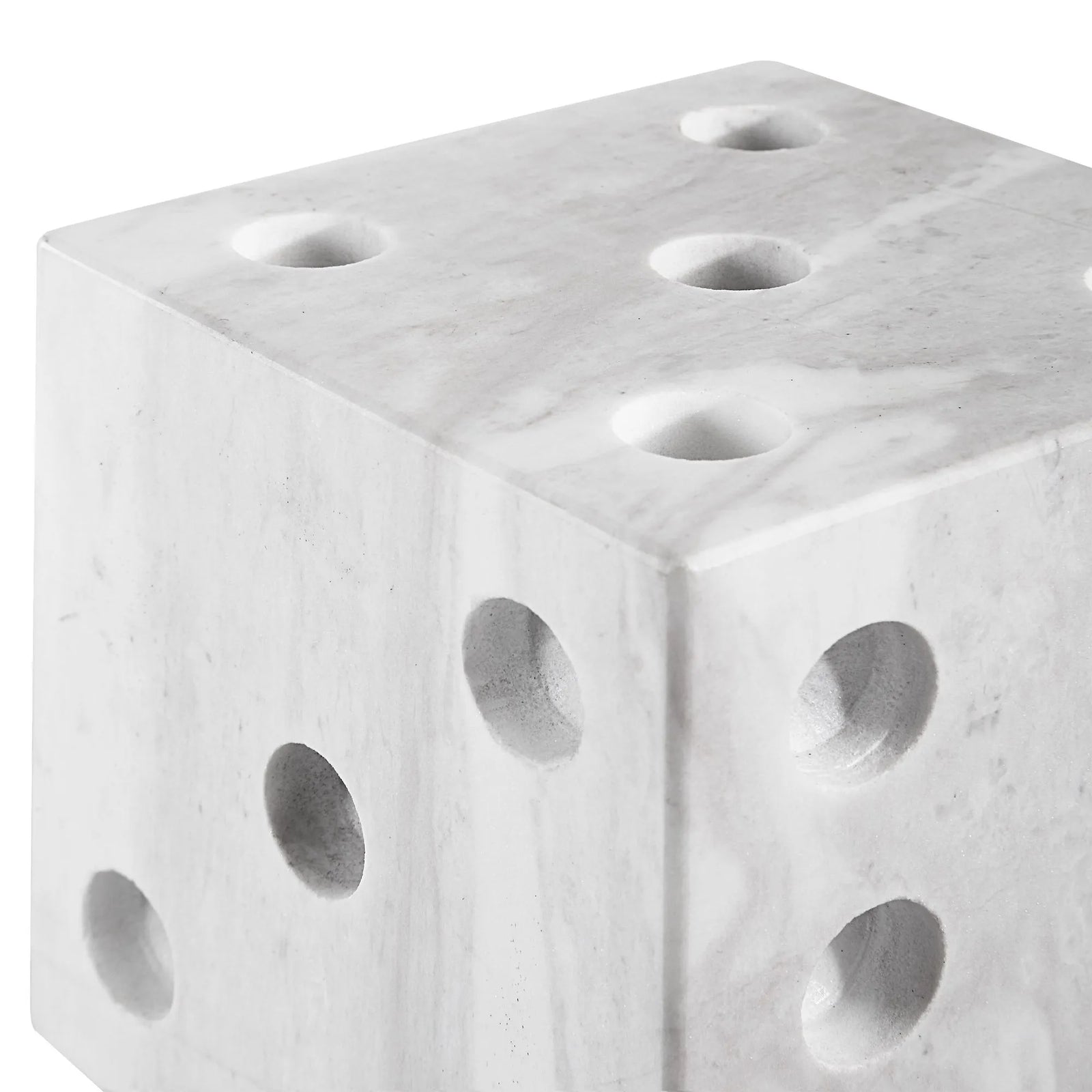 close-up to a gray marble dice decor object with multiple holes on each face, resembling dice numbers.