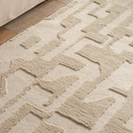 Close-up of a textured beige rug with geometric pattern on a wooden floor.