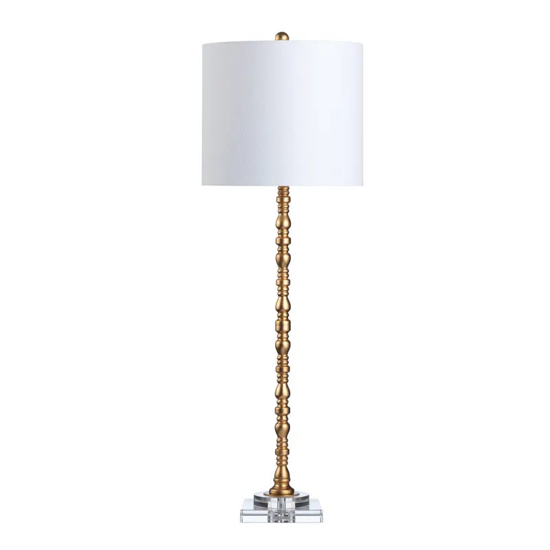A brass table lamp with a white shade, featuring a twisted stem design on a crystal base.
