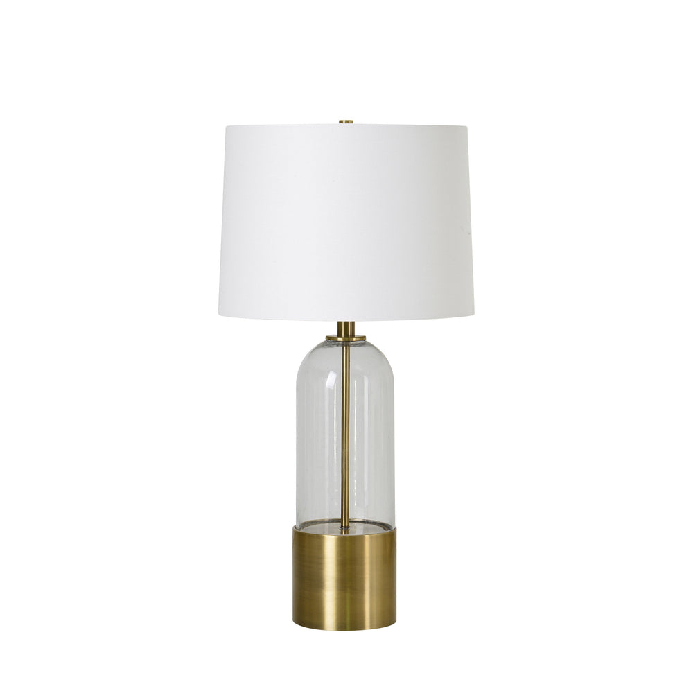 A mid-century modern table lamp with antique brass plated iron base and clear glass element, topped with an off-white shade.