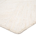 Close-up of a braided white rug corner on a light background