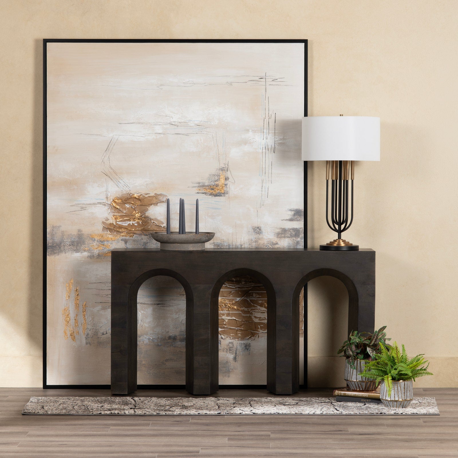 Decorative console table with abstract art and lamp against a beige wall