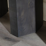 Close-up of a dark gray stone pedestal on a wooden floor.