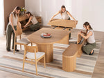 People assembling a wooden dining set in a room with a striped rug.