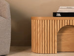 Wooden side table with a stack of books on a neutral background