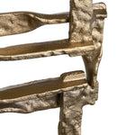 A set of two gold-colored metal decorative objects with a geometric design, placed on a dark base.