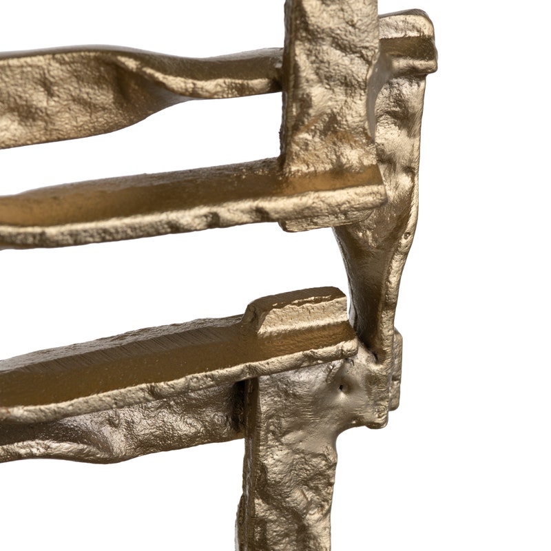 A set of two gold-colored metal decorative objects with a geometric design, placed on a dark base.