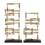 A set of two gold-colored metal decorative objects with a geometric design, placed on a dark base.