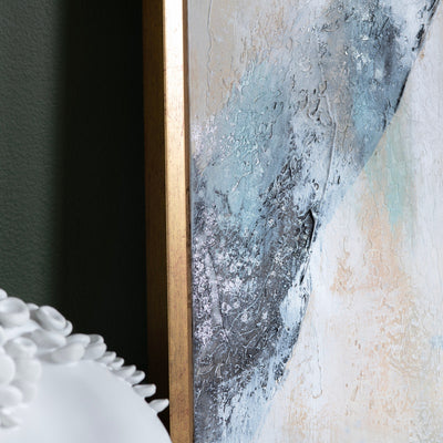 A framed abstract painting featuring shades of blue and white with gold accents, creating a serene ocean-like effect.