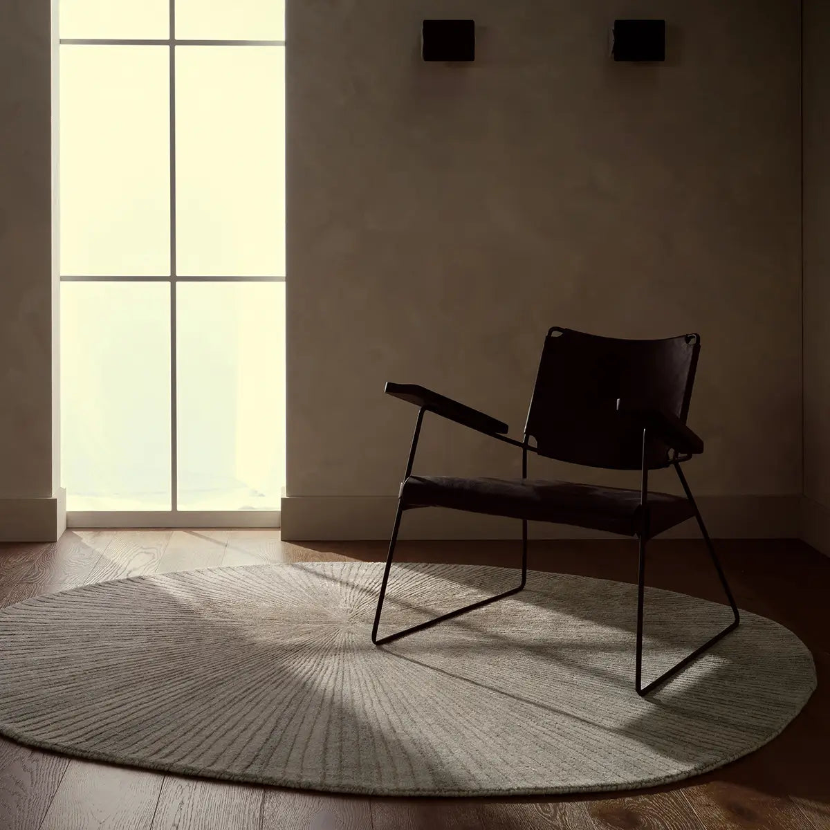 Modern black chair in a minimalistic room with a large window.