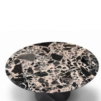 Round terrazzo table with a black and beige pattern on a white background