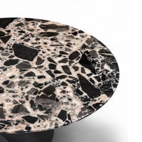 Round terrazzo table with a black and white pattern on a white background