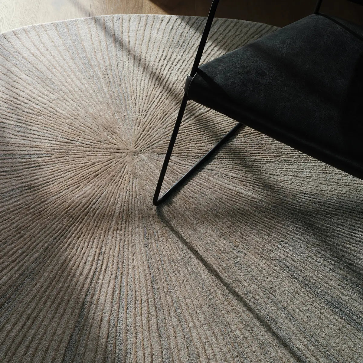 Round textured rug with a chair casting a shadow on it