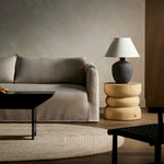 Modern living room with a gray sofa, wooden side table, and lamp.