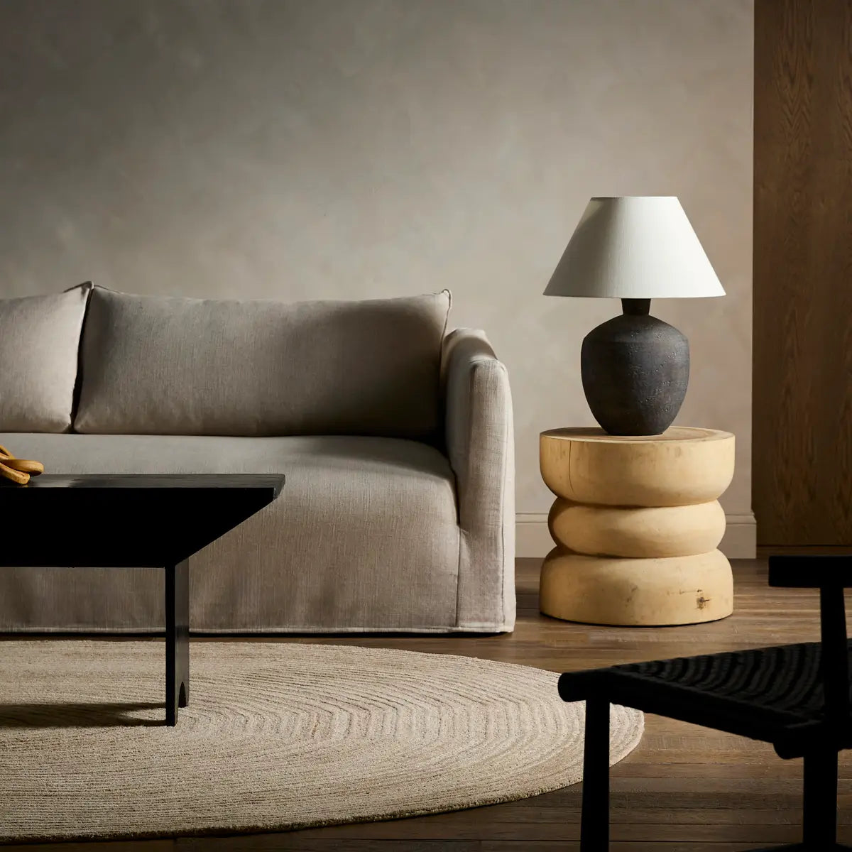 Modern living room with a gray sofa, wooden side table, and lamp.