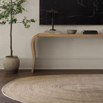 Modern interior with a wooden console table, plant, and round woven rug.