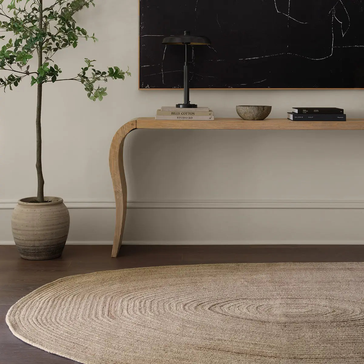 Modern interior with a wooden console table, plant, and round woven rug.