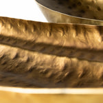 close up to two antique gold hammered bowls on a white background, designed to resemble oversized boat trays.