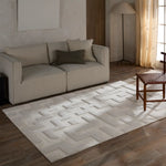 Beige sofa with decorative pillows on a geometric patterned rug in a living room.