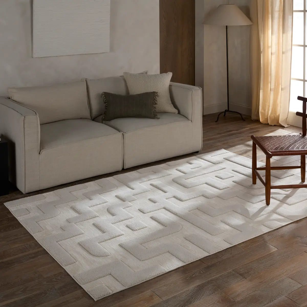 Beige sofa with decorative pillows on a geometric patterned rug in a living room.