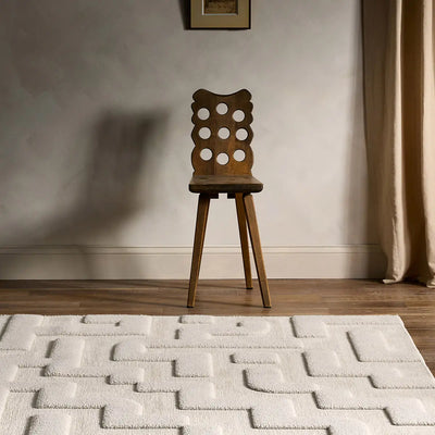 Wooden chair on a textured rug with a neutral wall and curtain in the background