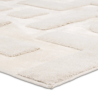 Close-up of a textured white rug with a diamond pattern on a light gray background