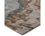 A rectangular area rug featuring a geometric pattern with shades of gray, blue, green, and brown.