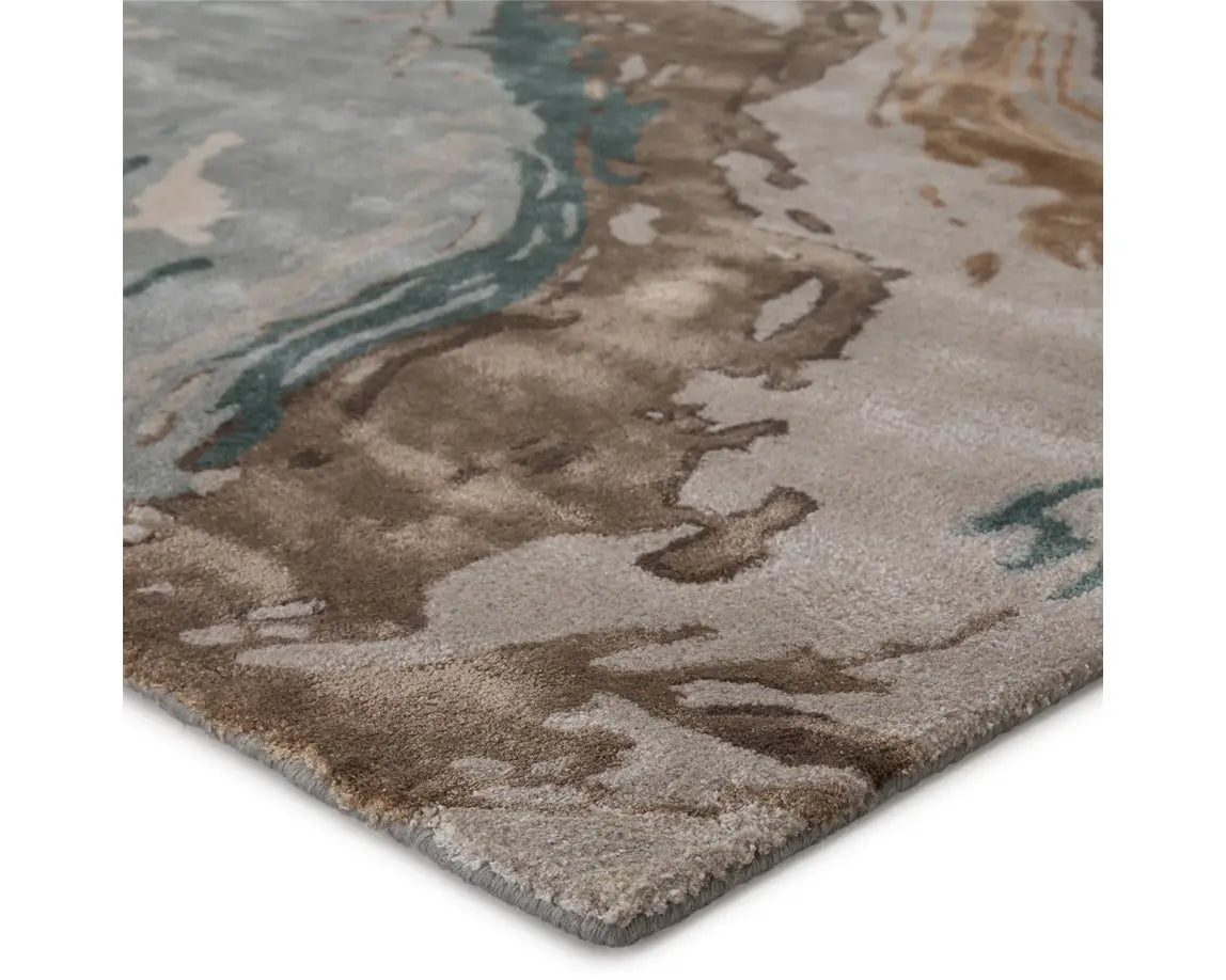 A rectangular area rug featuring a geometric pattern with shades of gray, blue, green, and brown.