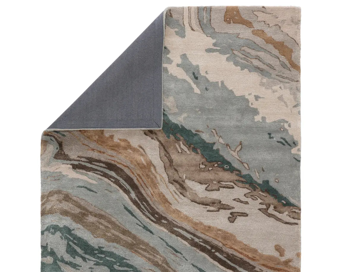 A rectangular area rug featuring a geometric pattern with shades of gray, blue, green, and brown.