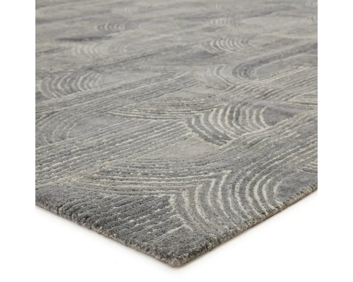 A rectangular wool area rug with a geometric pattern in gray, beige, and other colors.