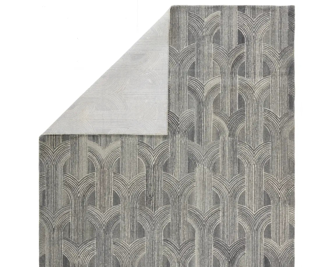 A rectangular wool area rug with a geometric pattern in gray, beige, and other colors.
