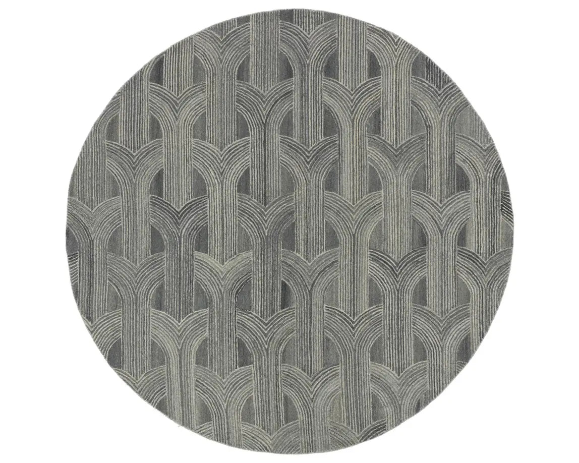 A round wool area rug with a geometric pattern in gray, beige, and other colors.