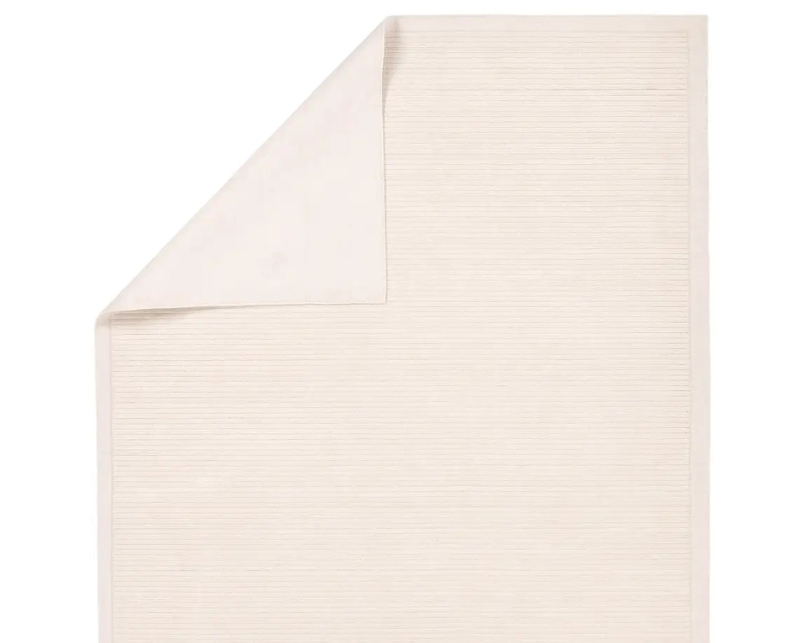 A beige, solid-colored area rug with a visible texture.