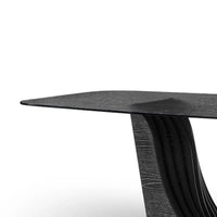 Black round dining table with wavy base design on a white background