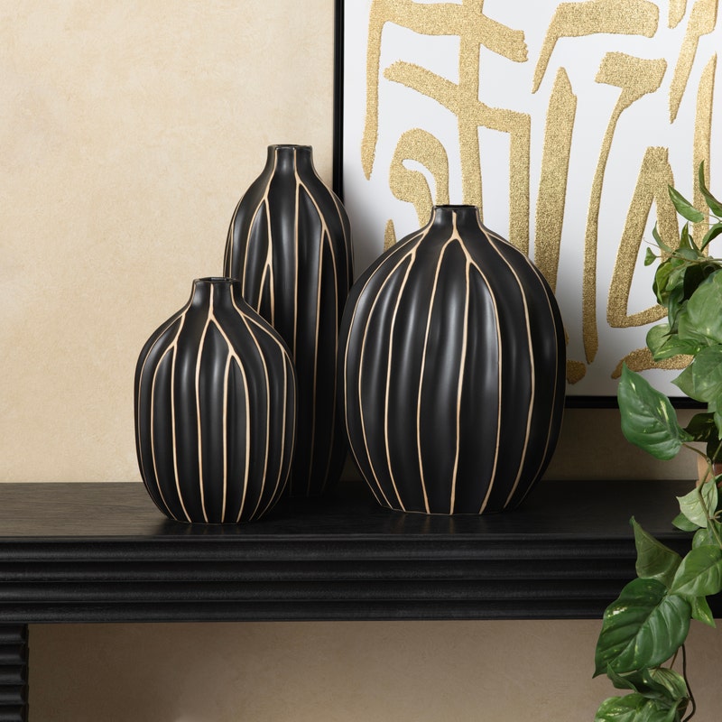 A set of three black vases with vertical golden stripes.