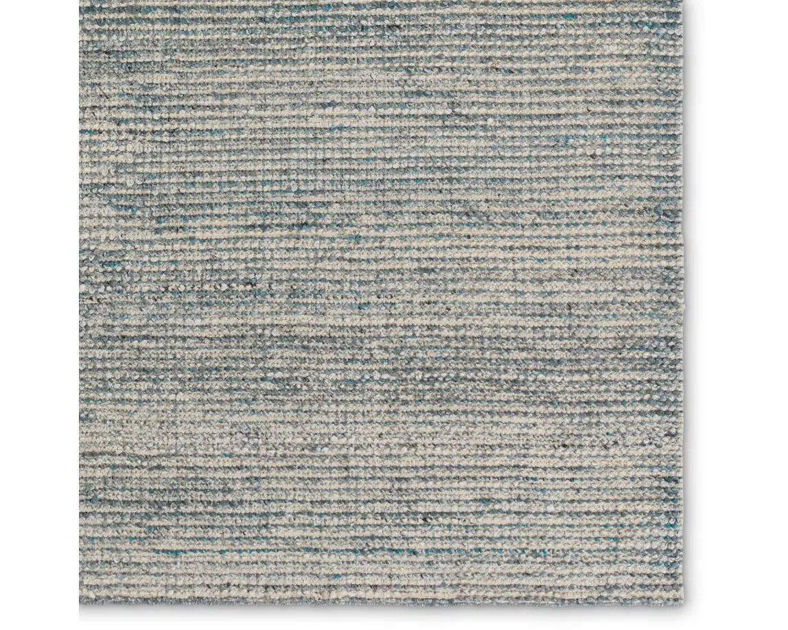 A rectangular area rug with a striped pattern in shades of blue and gray.