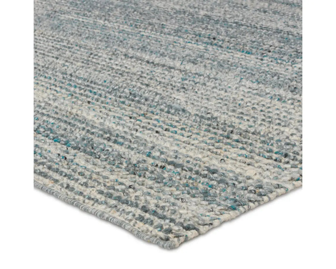 A rectangular area rug with a striped pattern in shades of blue and gray.