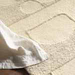 Close-up of a textured beige carpet with a white fabric draped over it