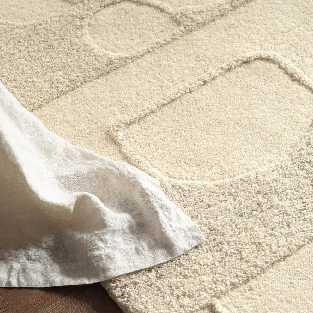 Close-up of a textured beige carpet with a white fabric draped over it