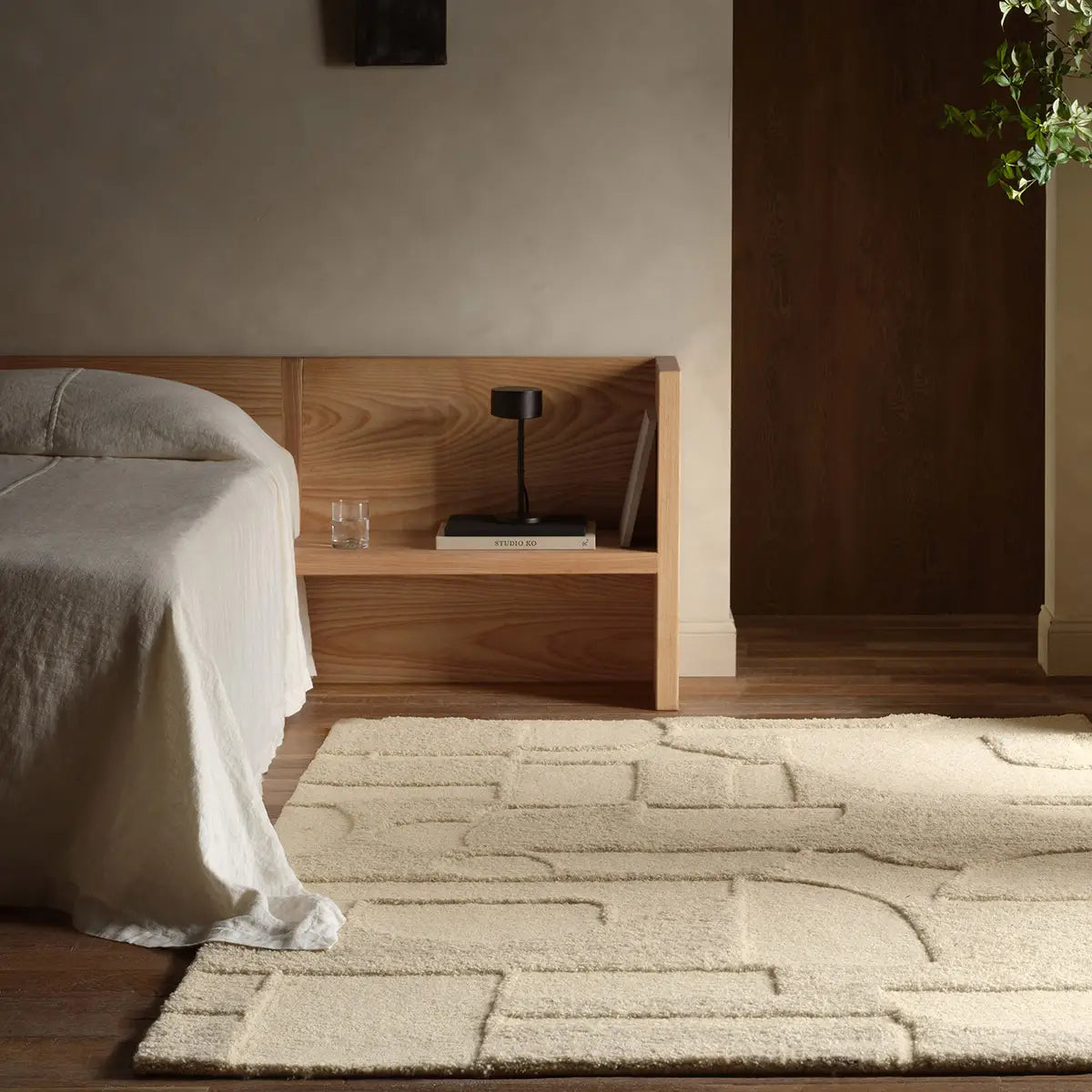 Modern bedroom with wooden headboard, bed, and rug.