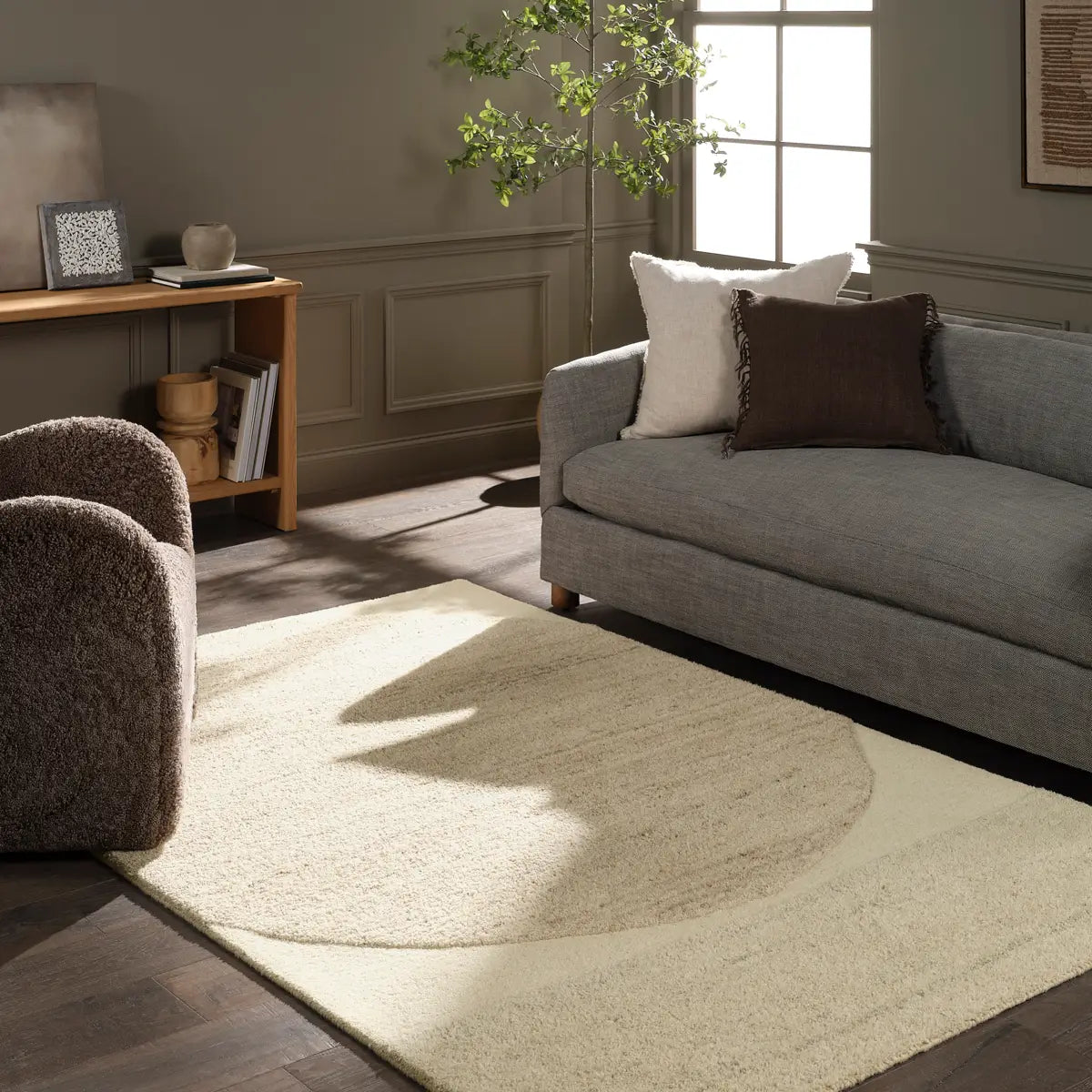 Living room with a gray sofa, armchair, and round beige rug.