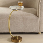 Gold side table with a glass of juice on a beige sofa