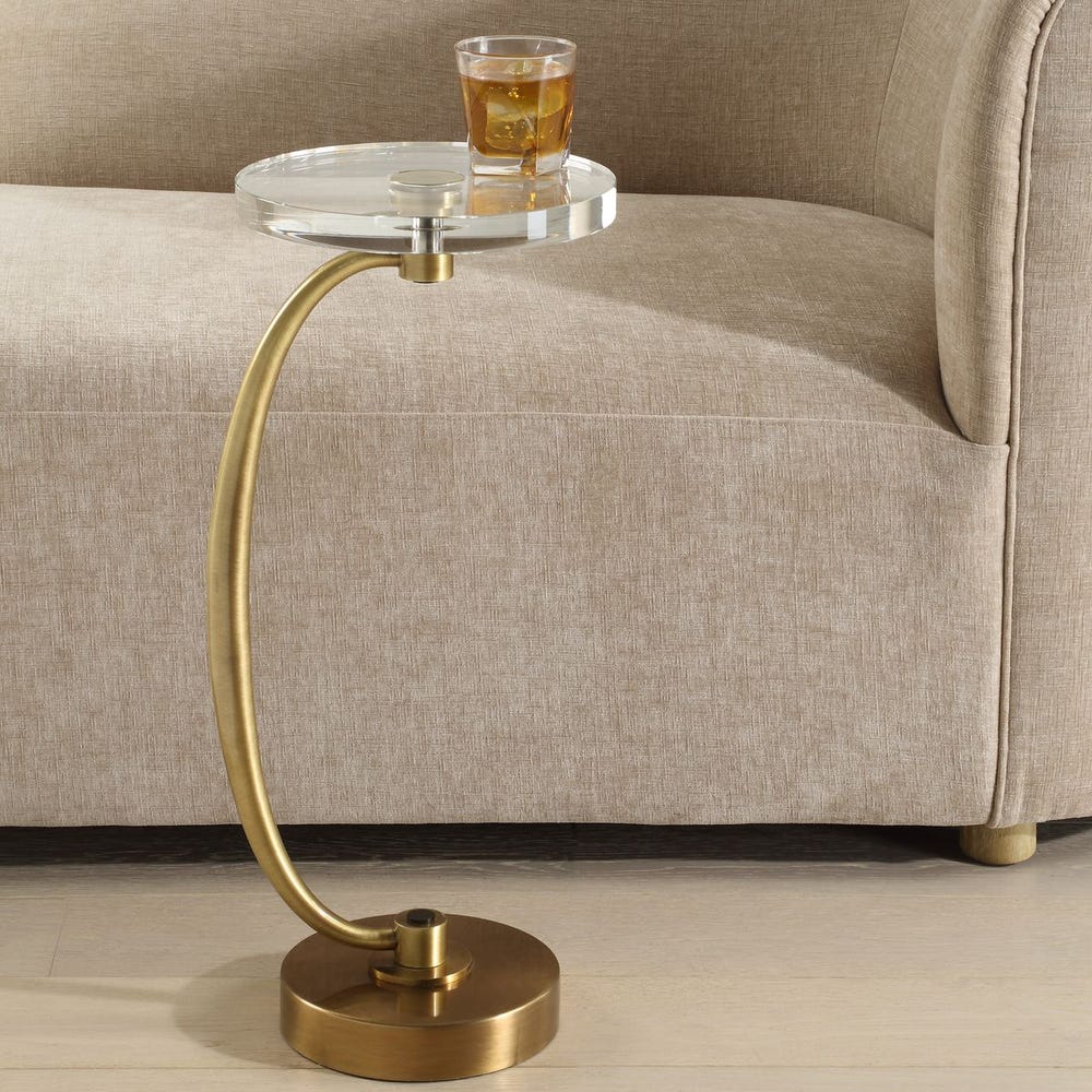 Gold side table with a glass of juice on a beige sofa